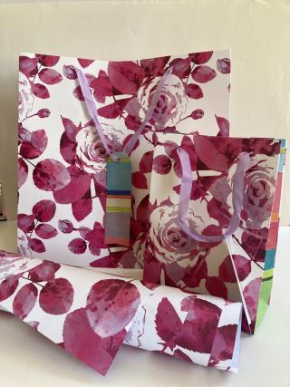 Geschenkpapier und verschieden große Geschenktaschen mit Rosen-Design.
