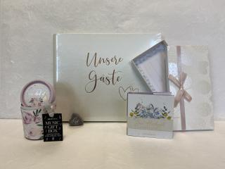 Weißes Gästebuch mit dem Aufdruck Unsere Gäste und zwei Herzen, kleine Music-Gift-Box in blumigem Design, Geschenkbüchlein mit dem Titel Zur Hochzeit die besten Wünsche, Gutscheinbox mit Schleife. 
Führt zu unseren weiteren Artikeln 