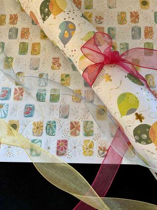 Geschenkpapier  weiß gemustert und verschiedenfarbige Bänder.
