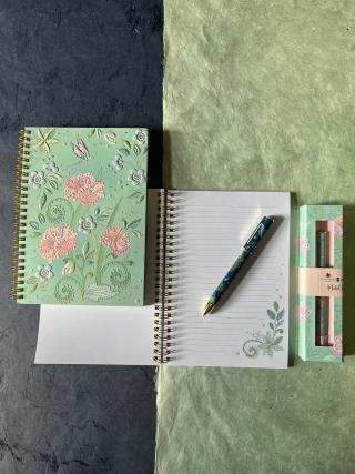 Spiralnotizbücher und Kugelschreiber mit Blumenmotiv.