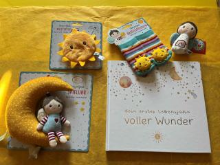 Spieluhr in der Form eines Mondes auf dem ein Kind sitzt, gelbes Knistertuch in Form einer Sonne, bunt gestreifte Rasselsöckchen mit Sonnen, Mini-Rassel und Buch 