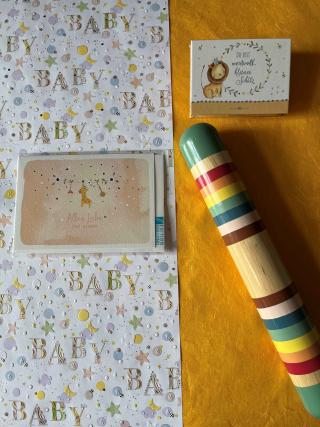 Billett mit dem Aufdruck Alles Liebe zur Geburt, Schatzkiste mit kurzen Gebeten, Effektinstrument Regenmacher.