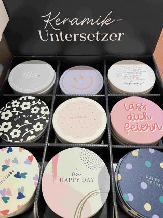 Keramik-Untersetzer mit verschiedenen Motiven und Sprüchen.