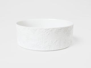 Keramikschale mit Blüten und Blättern am Rand.